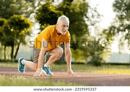 Handsome Caucasian gray haired bearded senior athletic man, runner in sportswear, stands at the starting position on the treadmill, ready for morning run. Running. Jogging. Marathon. Cardio workout  Royalty-Free Stock Photo #2319595337