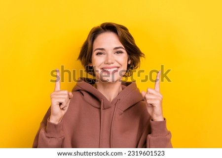 Portrait of cute cheerful person beaming smile indicate fingers up empty space isolated on yellow color background
