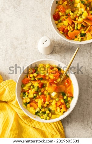 Minestrone soup from zucchini and tomato, onion and carrot, corn and peas with parsley, top view of soup plates, vegetarian soup Royalty-Free Stock Photo #2319605531