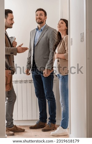 A young couple with a real-estate agent visiting an apartment for sale or for rent. Married couple buying an apartment. Real estate concept. Royalty-Free Stock Photo #2319618179