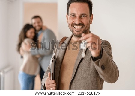 Portrait of a real estate agent in the apartment for sale or for rent.  A young married couple standing in the background. Real estate concept. Royalty-Free Stock Photo #2319618199