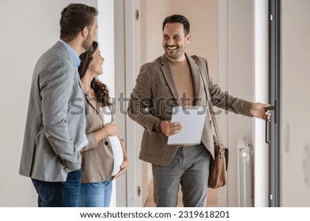 A young couple with a real-estate agent visiting an apartment for sale or for rent. Married couple buying an apartment. Real estate concept.