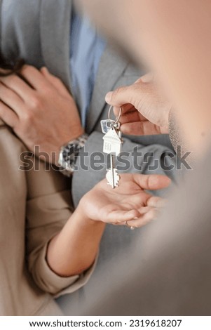 Close-up of real estate agent giving keys to couple with a focus on house keychain, copy space