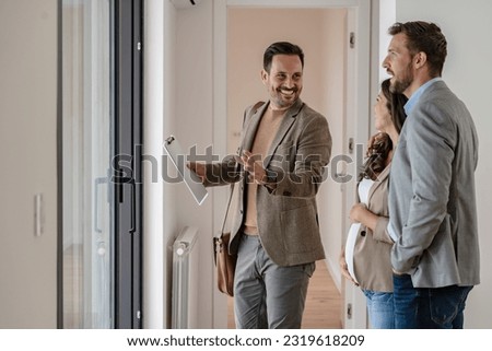 A young couple with a real-estate agent visiting an apartment for sale or for rent. Married couple buying an apartment. Real estate concept. Royalty-Free Stock Photo #2319618209