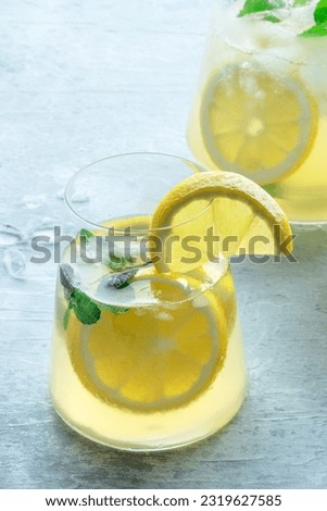 Lemonade with mint panorama. Lemon water drink with ice. A glass and a pitcher on a pastel background. Detox beverage. Fresh homemade cocktail
