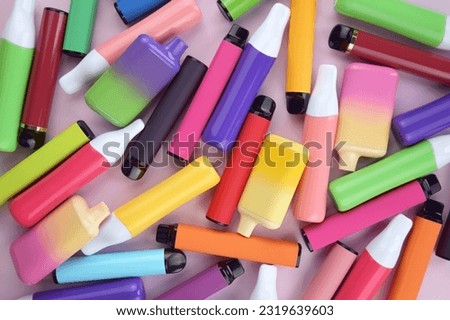 Set of multicolor disposable electronic cigarettes on a pink background. The concept of modern smoking, vaping and nicotine. Royalty-Free Stock Photo #2319639603