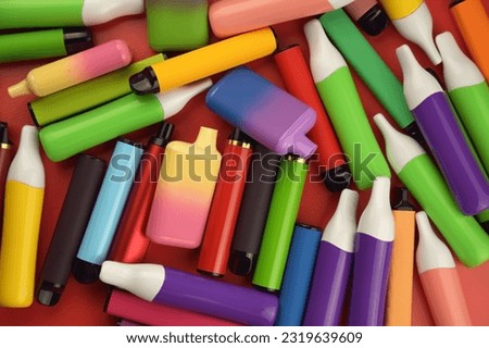 Set of multicolor disposable electronic cigarettes on a red background. The concept of modern smoking, vaping and nicotine. Royalty-Free Stock Photo #2319639609