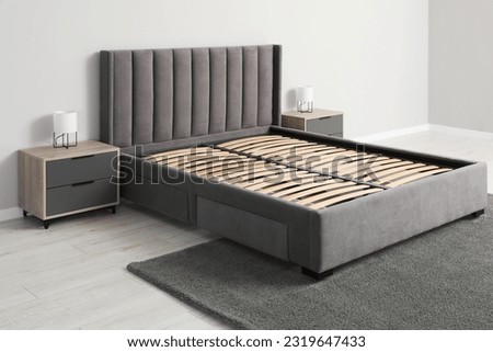 Comfortable bed with storage space for bedding under slatted base in room Royalty-Free Stock Photo #2319647433