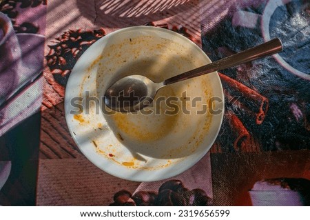 Empty plate with spoon on table in the morning light, stock photo.
