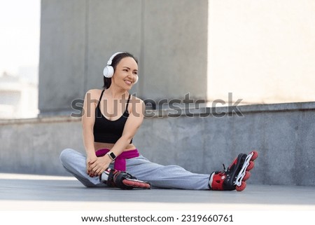 Smiling young woman in roller skates stretches before a ride. Music of freedom and active lifestyle.