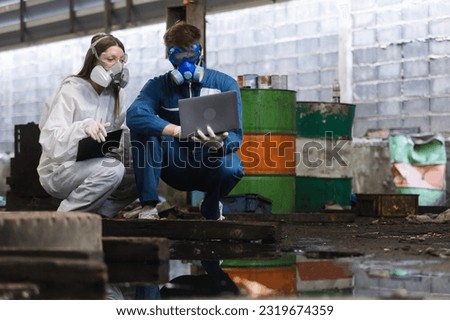Team inspector chemical and hazmat wearing protective mask using laptop and write note on clipboard. Wastewater chemical residue in factory. Analysing harmful substances to human body environment. Royalty-Free Stock Photo #2319674359