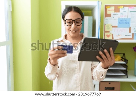 Young arab woman business worker using touchpad and credit card at office