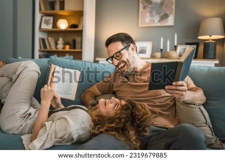 Adult couple man and woman Caucasian husband and wife in a relationship real book hold books on the sofa bed at home in the apartment reading leisure bonding family concept real people copy space Royalty-Free Stock Photo #2319679885