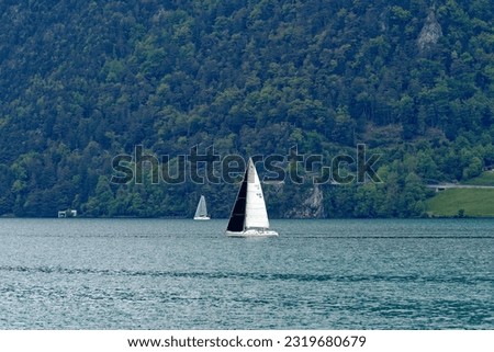 Scenic view of sailing boats on Lake Lucerne seen from pier of Treib on a cloudy spring day. Photo taken May 18th, 2023, Treib, Canton Uri, Switzerland.