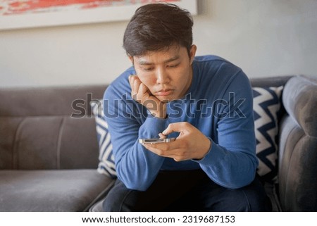 close up asian teenager man feeling bored while playing smartphone at house for teenage and technology life concept