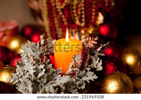 Christmas decorations with candle and christmas balls. Horizontal image in warm red and orange colors. Calm mood