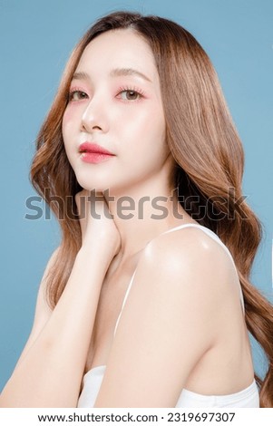 Young Asian beauty woman curly long hair with korean makeup style on face and perfect clean skin on isolated blue background. Facial treatment, Cosmetology, plastic surgery.