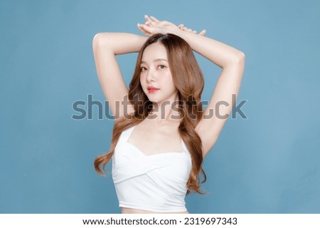 Young Asian beauty woman curly long hair with korean makeup style on face and perfect clean skin show armpits on isolated blue background. Facial treatment, Cosmetology, plastic surgery.