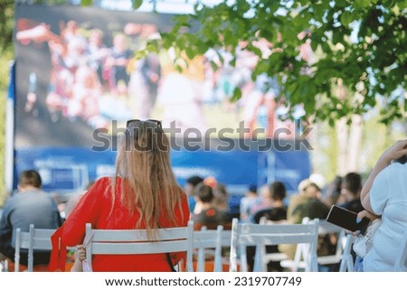 People sit in a summer open-air cinema Royalty-Free Stock Photo #2319707749