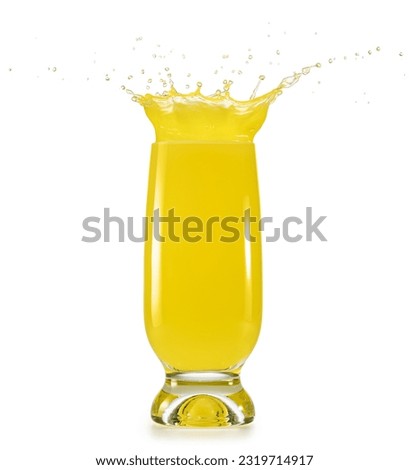 Overflowing glass of yellow liquid isolated on white background. Splashing refreshing pineapple juice.