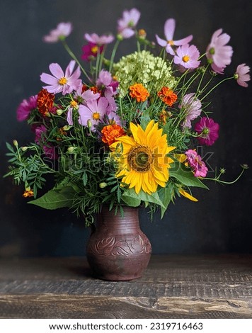 Bouquet of flowers in an old jug on a wooden table with black background. Still life with marigolds, decorative sunflower, kosmeya, hydrangea in the flower arrangement.  Royalty-Free Stock Photo #2319716463