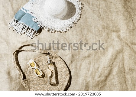 Summer vacation, beach rest concept, aesthetic flat lay fashion beach bag, white sun hat, sunglasses, detox drink lemon water on beach towel at sunlight, lifestyle trendy vintage toned photo, top view