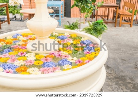 Mixed colorful flowers floating in water in classic style fountain.