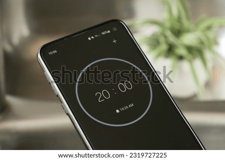 A phone with a black and white 20-minute timer to study with the pomodoro method on a blurry background Royalty-Free Stock Photo #2319727225