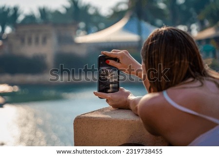 A young woman takes a picture of the Dubai Waterfront Promenade with her mobile phone.