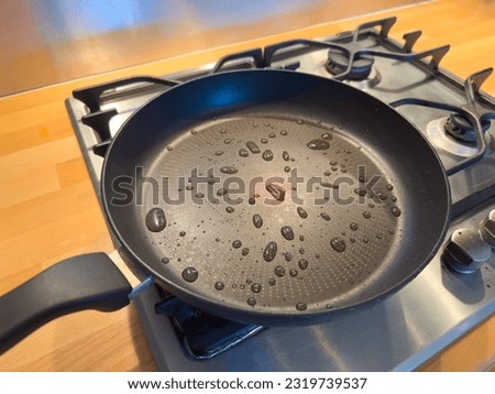 Drops on Teflon coated pan on stove. Potential dangerous chemicals in cookware, non stick frying. PFAS or  perfluoroalkyl. Part of a serie. Royalty-Free Stock Photo #2319739537