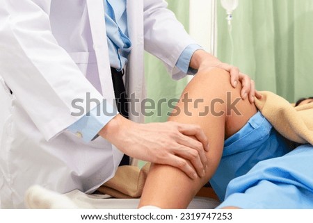 An Asian doctor checks the knees of an obese patient lying on a nursing bed. The concept of osteoarthritis in obese people. Hospital medical services Royalty-Free Stock Photo #2319747253