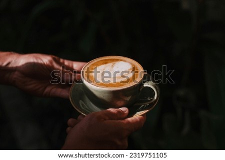 A man holds a ceramic mug with a cappuccino. Delicious coffee in the morning Royalty-Free Stock Photo #2319751105