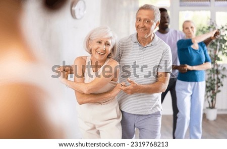 Group of multinational sports aged people rehearsing social dance in dance hall Royalty-Free Stock Photo #2319768213