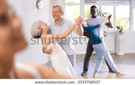 Group of multiethnic mature active people dancing social dance movements in studio Royalty-Free Stock Photo #2319768337