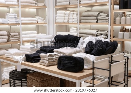 A shop window with bed linen, pillows and blankets in warm shades. Towels and bark with textiles on the shelves