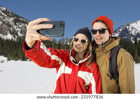 Young couple taking a selfie in front of a beautiful winter landscape during their wintersport