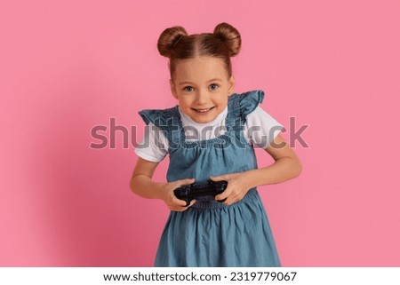 Excited Little Girl Playing Video Games With Joystick While Standing Over Pink Studio Background, Happy Preteen Female Child Having Fun, Enjoying Modern Gadgets For Leisure, Copy Space