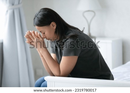 Depressed tired mixed raced woman feeling sorrow, burnout and fatigue, coping with loss, grief or apathy, suffering from mental health disorder or nervous breakdown, sitting on bed with closed eyes. Royalty-Free Stock Photo #2319780017