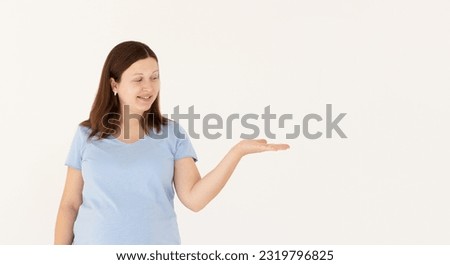Beautiful caucasian woman expecting a baby, touching pregnant belly smiling cheerful presenting and pointing with palm of hand looking at the camera.