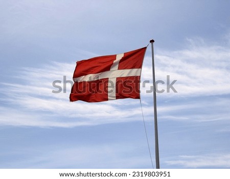 You see the flag of denmark, blowing in the wind.
