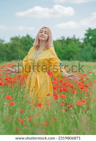 Girl in yellow with blue elements embroidered Boho dress. Fashionable blonde head lady in poppy field