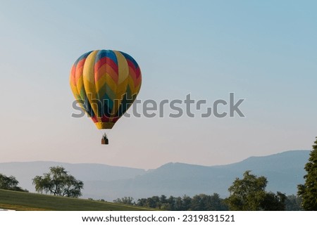 A brightly colored hot air balloon over a mountainous landscape in Wytheville Virginia during the Chautauqua Balloon Festival. Royalty-Free Stock Photo #2319831521
