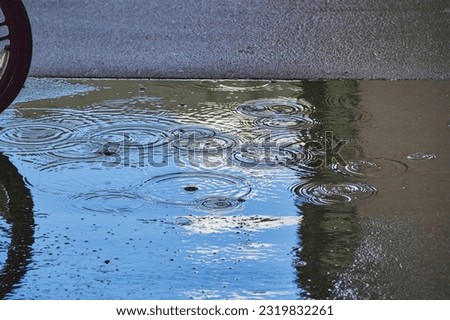 a puddle on the asphalt with a reflection of the blue sky during when it rains