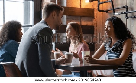 Happy young diverse people enjoying speed dating communication, discussing common interests in cozy cafeteria. Shy millennial generation mixed race men and women chatting talking at meeting. Royalty-Free Stock Photo #2319854243
