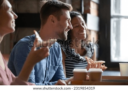 Happy young caucasian man enjoying spending carefree leisure weekend time in cafe with mixed race diverse mates, having fun joking communicating, entertaining together, friendship relations concept. Royalty-Free Stock Photo #2319854319