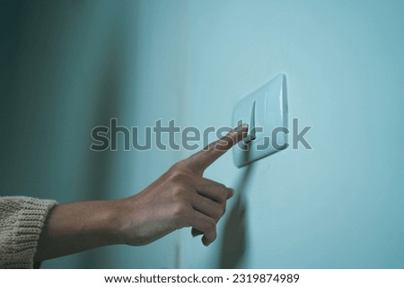 Earth Hour Close up woman finger turn off or on the light to saving electrical energy. Finger pushing light switch turn on or off. White switch Royalty-Free Stock Photo #2319874989