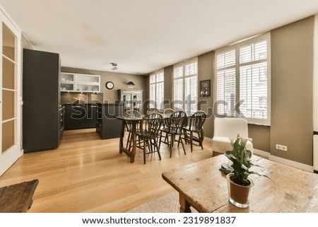 a kitchen and dining area in a living room with wood floors, hardwood flooring and white shuttered windows Royalty-Free Stock Photo #2319891837