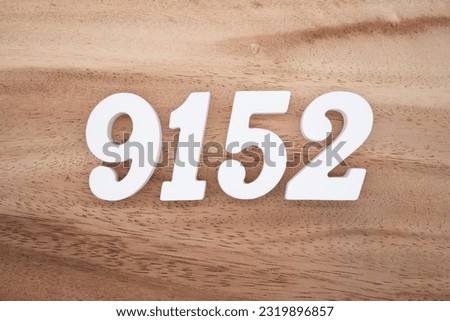 White number 9152 on a brown and light brown wooden background.