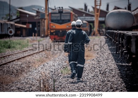 Back side view engineer railway under inspection and checking construction railway switch and maintenance work on railroad station .Engineer wearing safety uniform and safety helmet in work.