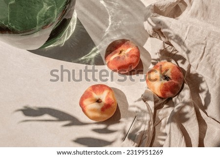 Ripe peaches on tan beige tabletop background with a abstract aesthetic sunlight shadows, summer fruit diet
